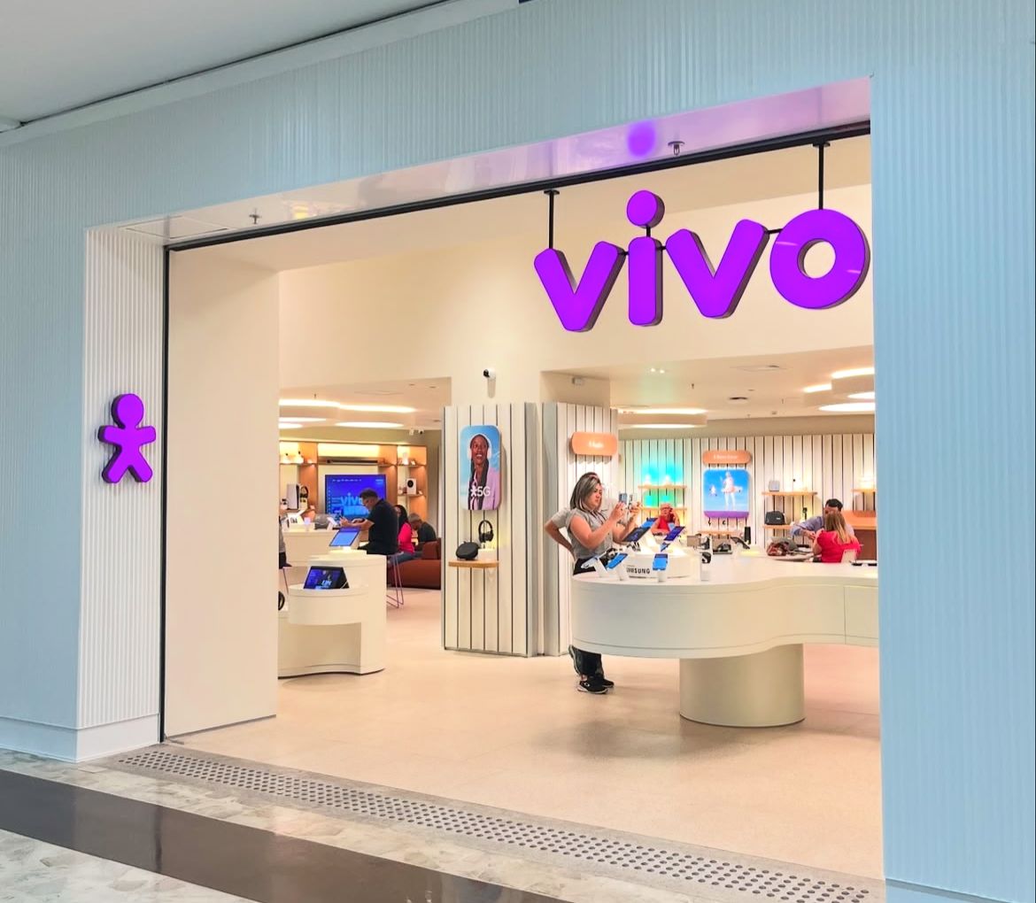 Fachada da loja Vivo com testeira roxa retroiluminada e boneco signature em shopping