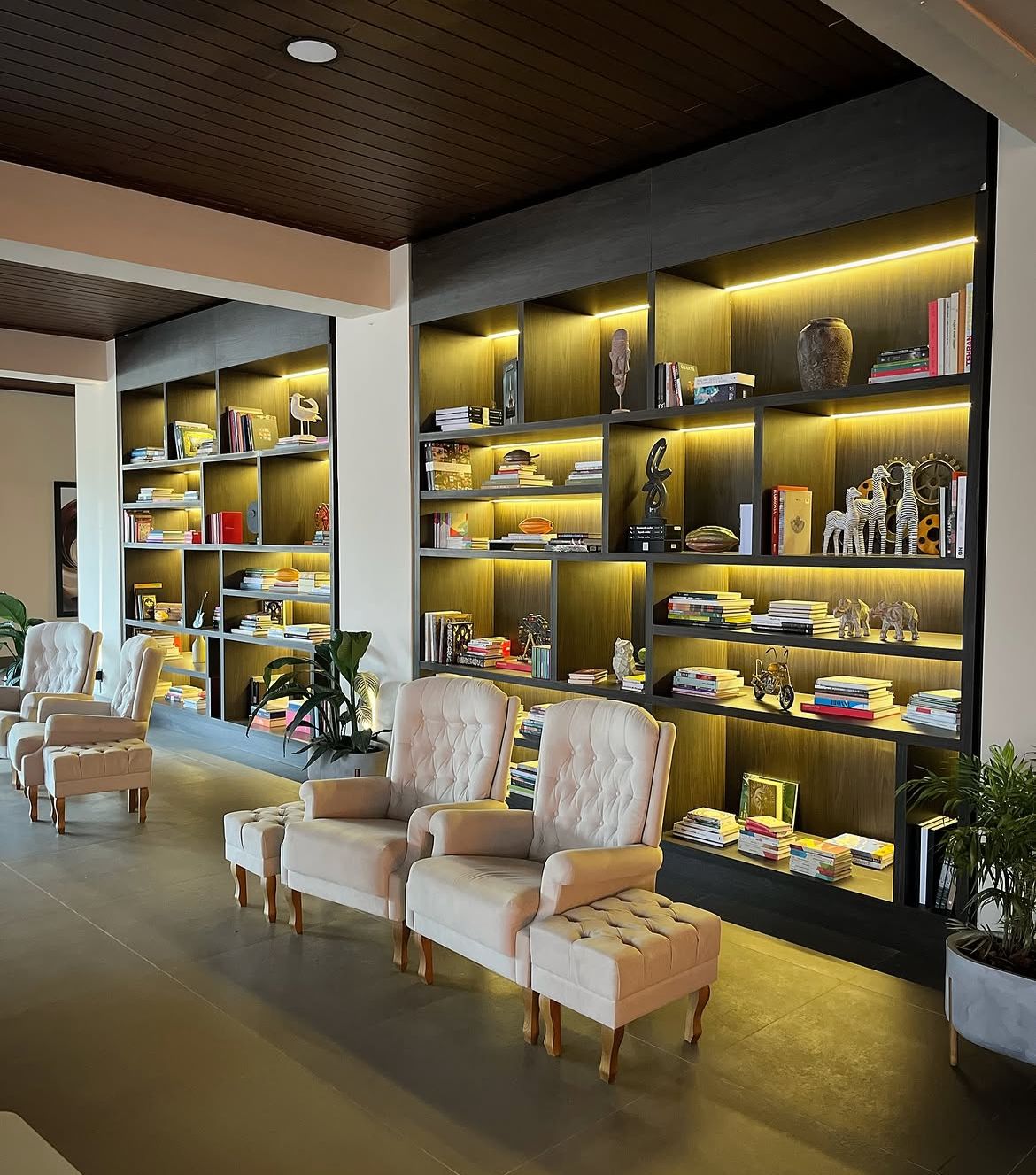Biblioteca lounge com estantes iluminadas