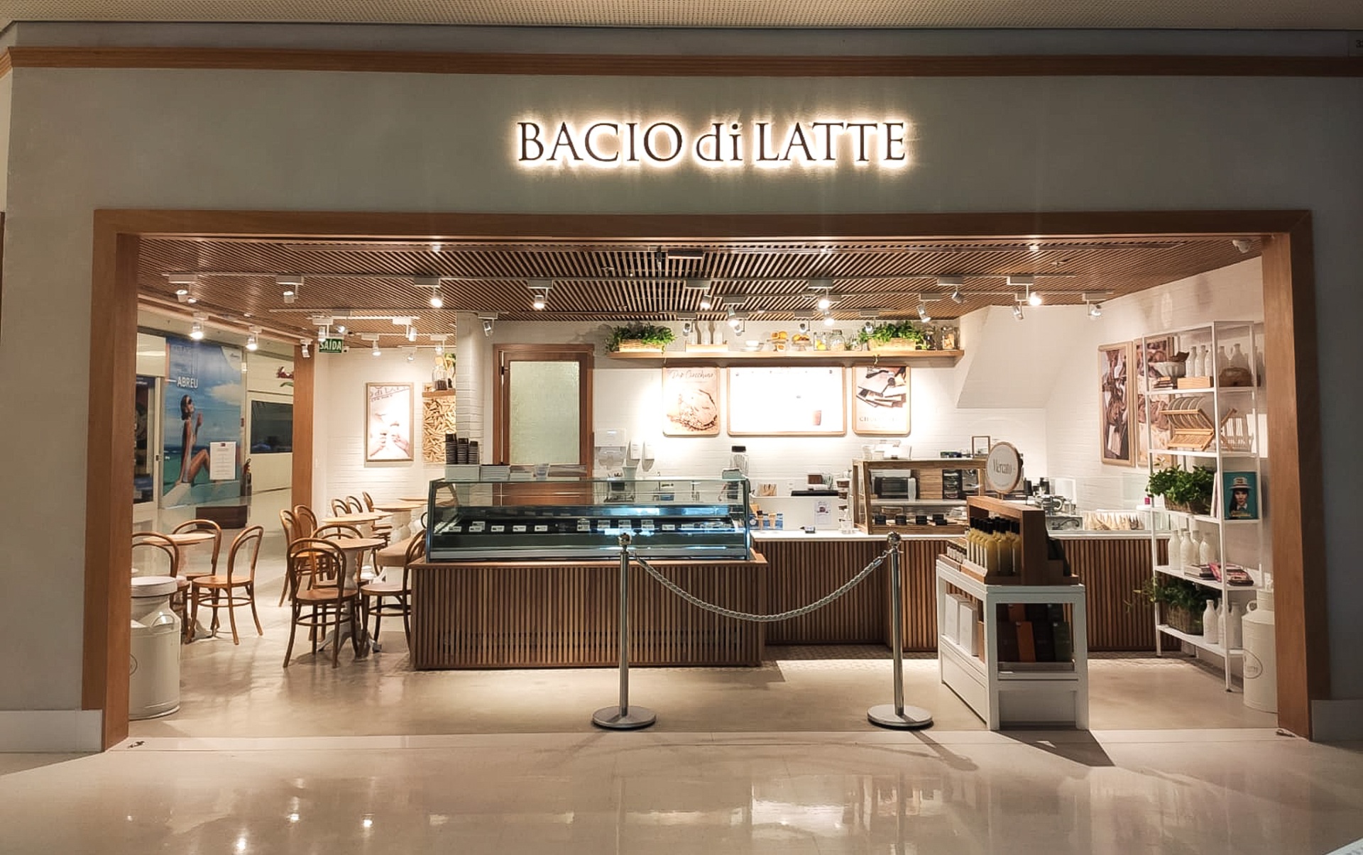 Fachada da loja Bacio di Latte com letreiro iluminado e teto ripado em madeira