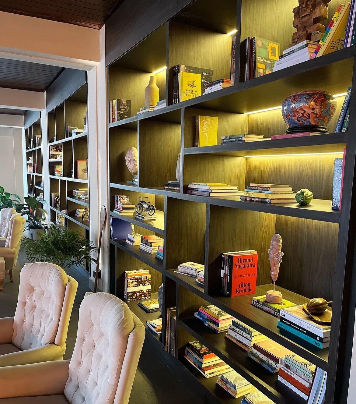 Detalhe da estante iluminada com curadoria de livros