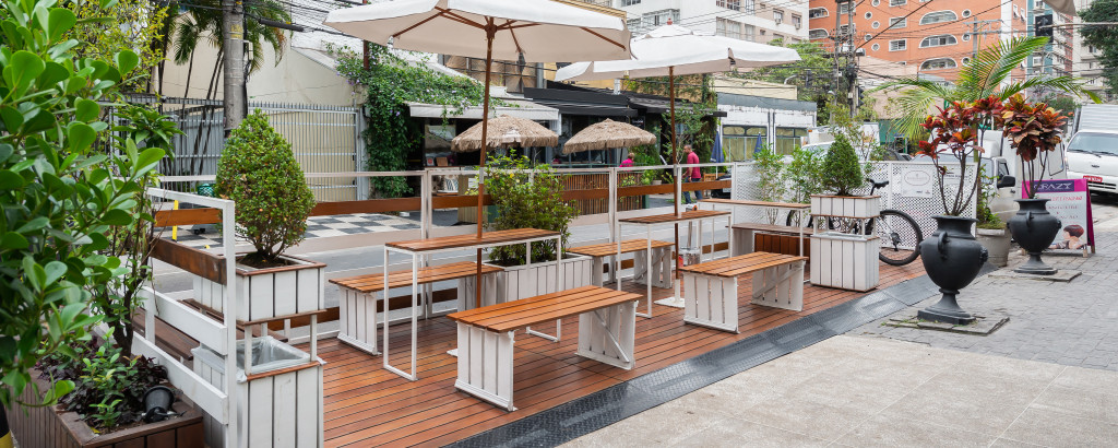 Deck externo em madeira com mesas, guarda-sóis e floreiras da loja Bacio di Latte
