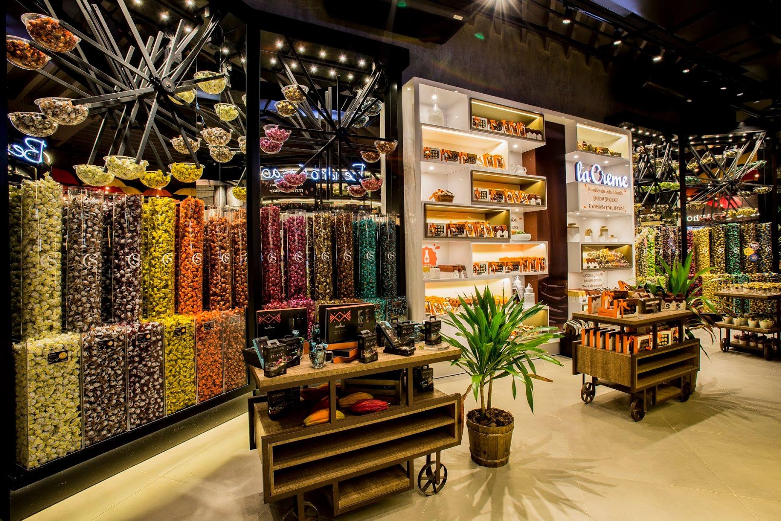 Vista da Mega Cacau Show com dispensers cilíndricos de granel, roda-gigante de doces e cafeteria La Creme ao fundo